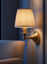Auberly pleated fabric drum wall sconce beside a reading chair