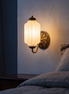 Lisette frosted milk glass wall sconce beside a bed